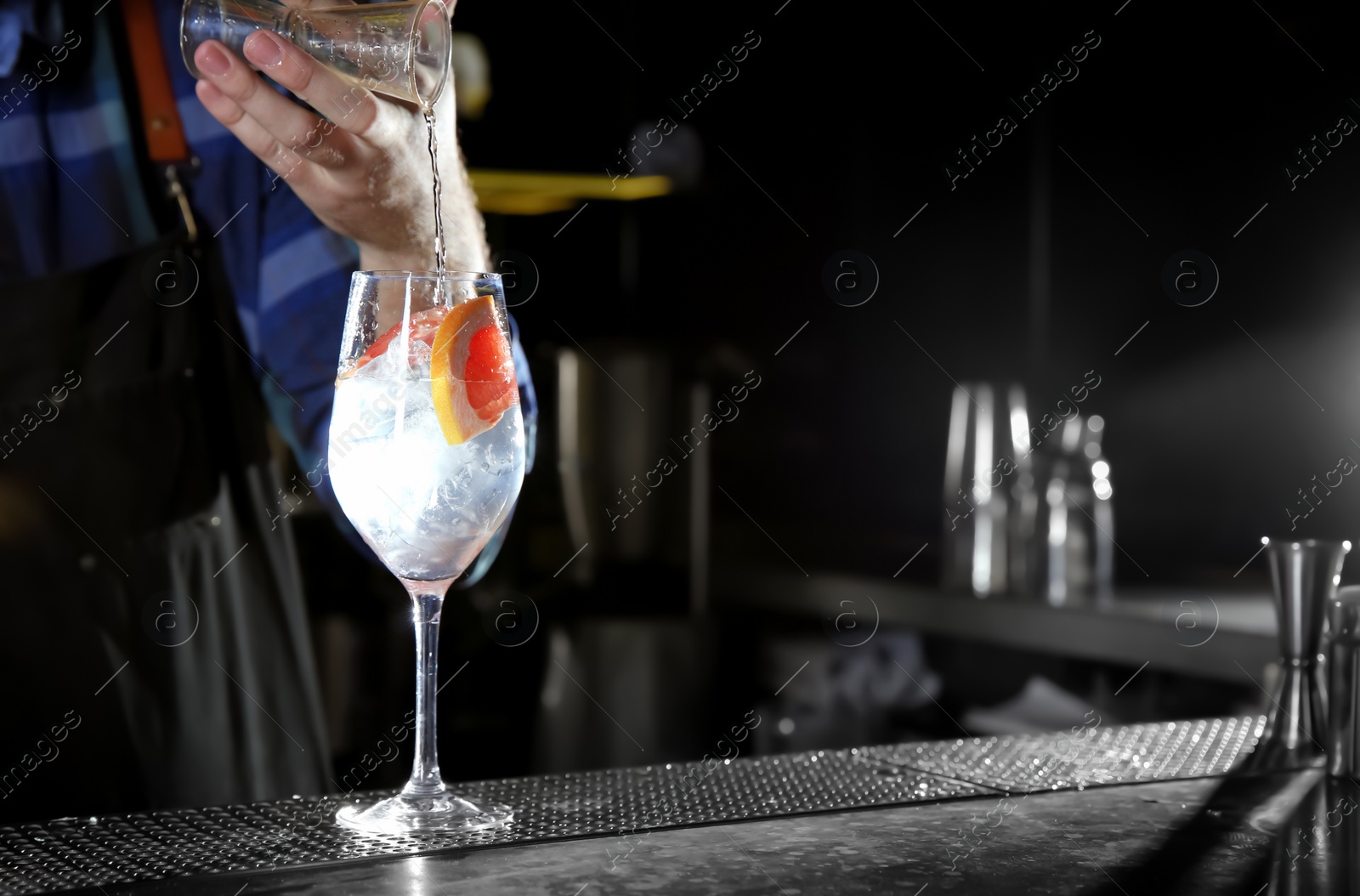 Photo of Barman making grapefruit gin tonic cocktail at counter in pub, closeup. Space for text