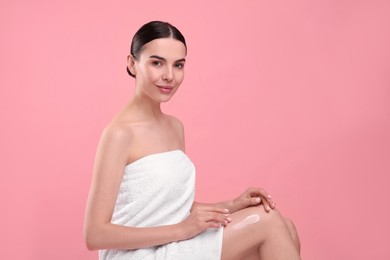 Photo of Beautiful woman with smear of body cream on her leg against pink background, space for text