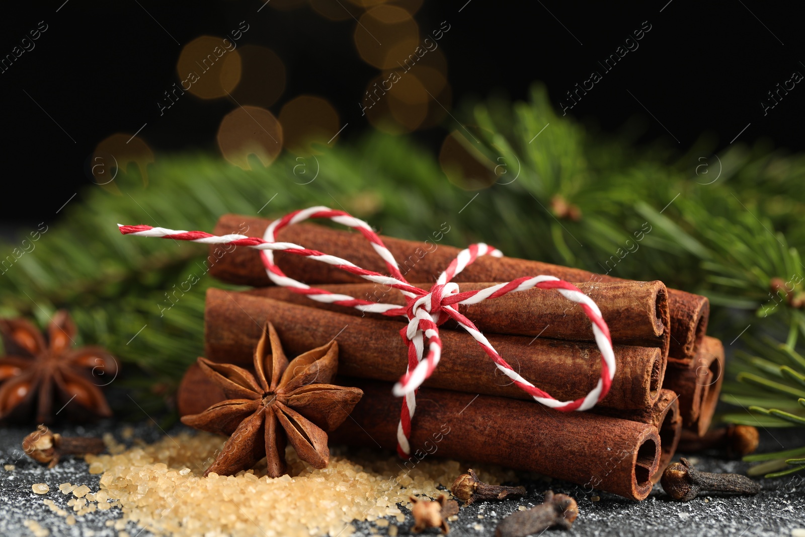 Photo of Different aromatic spices and fir branches on grey textured table, closeup