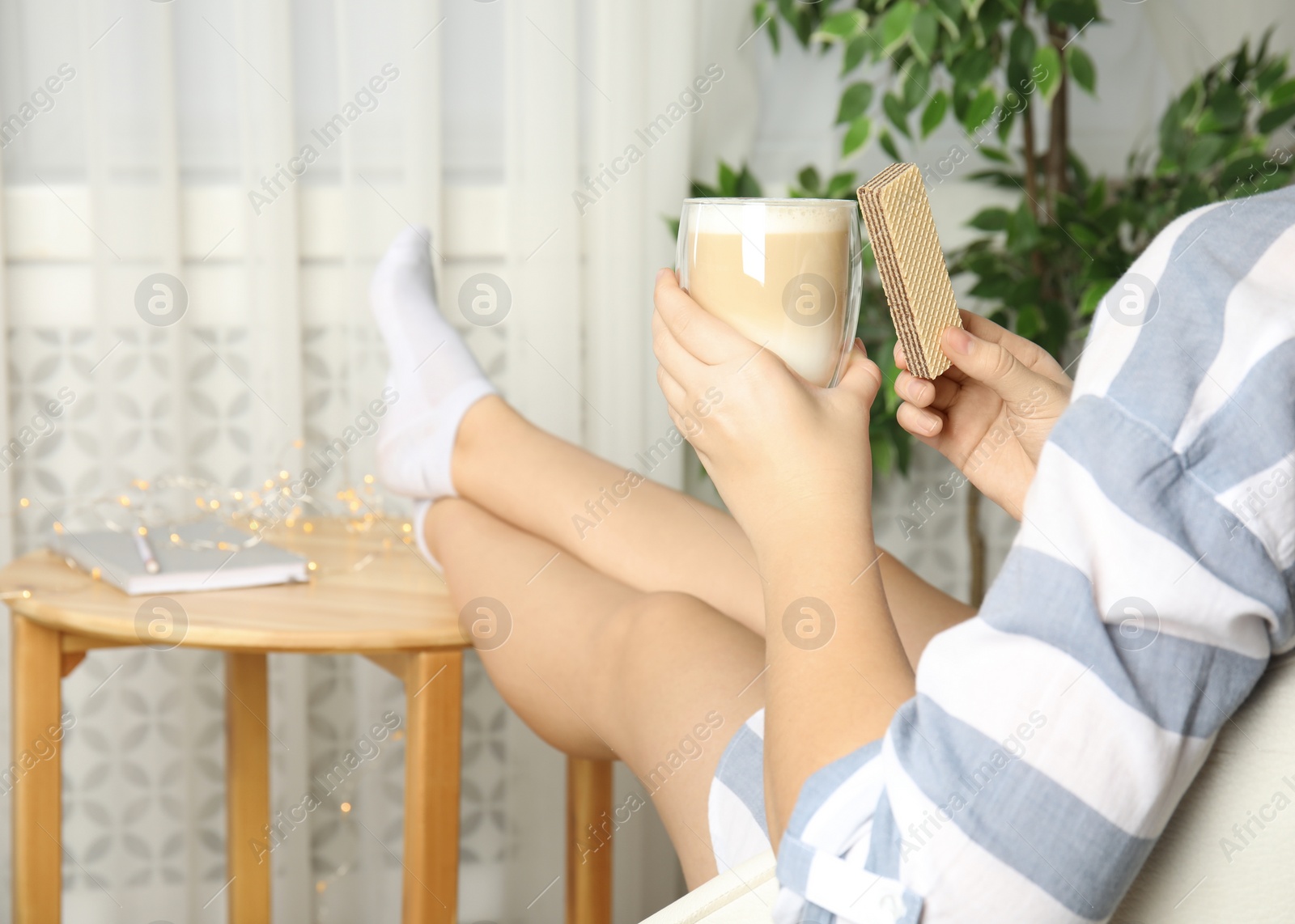 Photo of Woman having delicious wafer and coffee for breakfast indoors, closeup