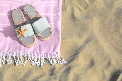 Photo of Pink blanket with stylish slippers and dry starfish on sandy beach, above view. Space for text