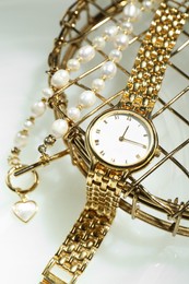 Photo of Stylish presentation of elegant wristwatch and pearl necklace on white background, closeup