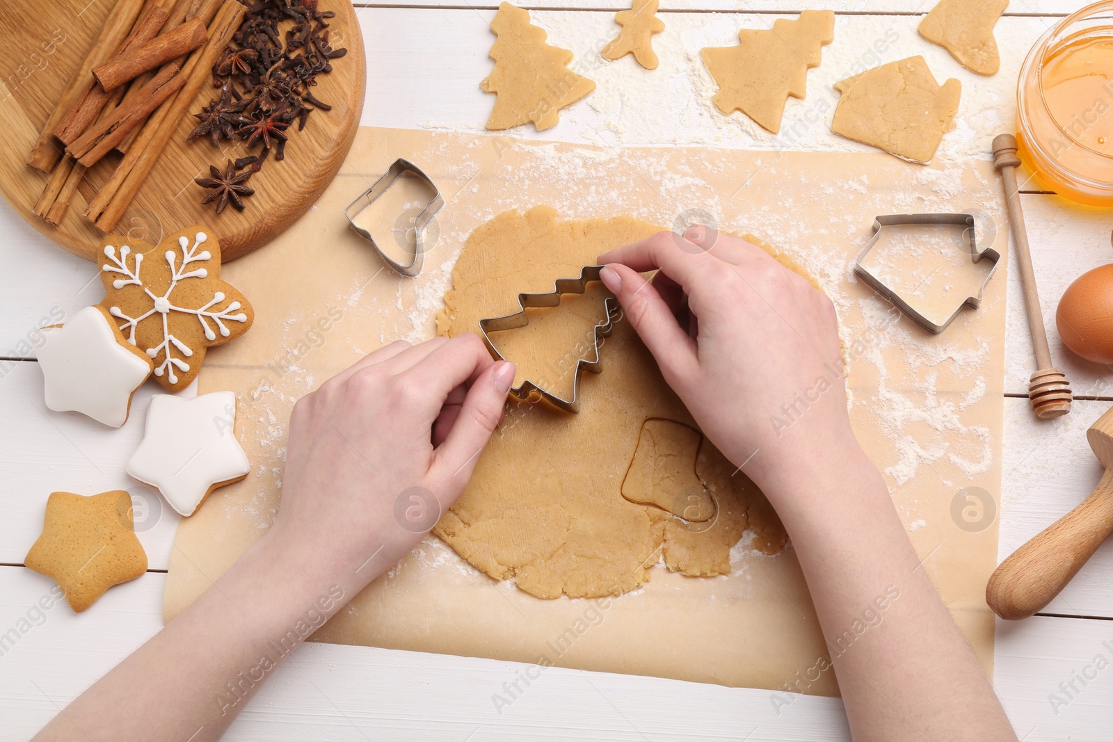 Photo of Woman making Christmas cookies with cutters at white wooden table, top view