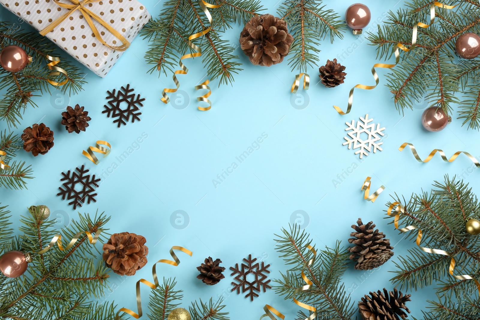 Photo of Frame of serpentine streamers and Christmas decor on light blue background, flat lay. Space for text