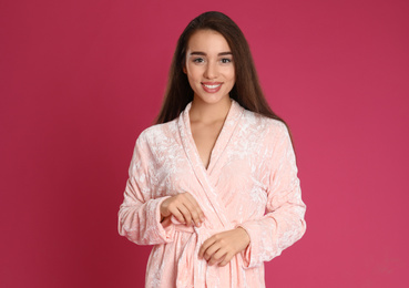 Photo of Young woman in bathrobe on crimson background