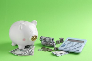 Financial savings. Piggy bank, dollar banknotes, coins and calculator on green background