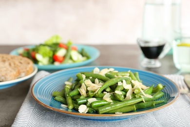 Photo of Plate with tasty green beans and almonds on table