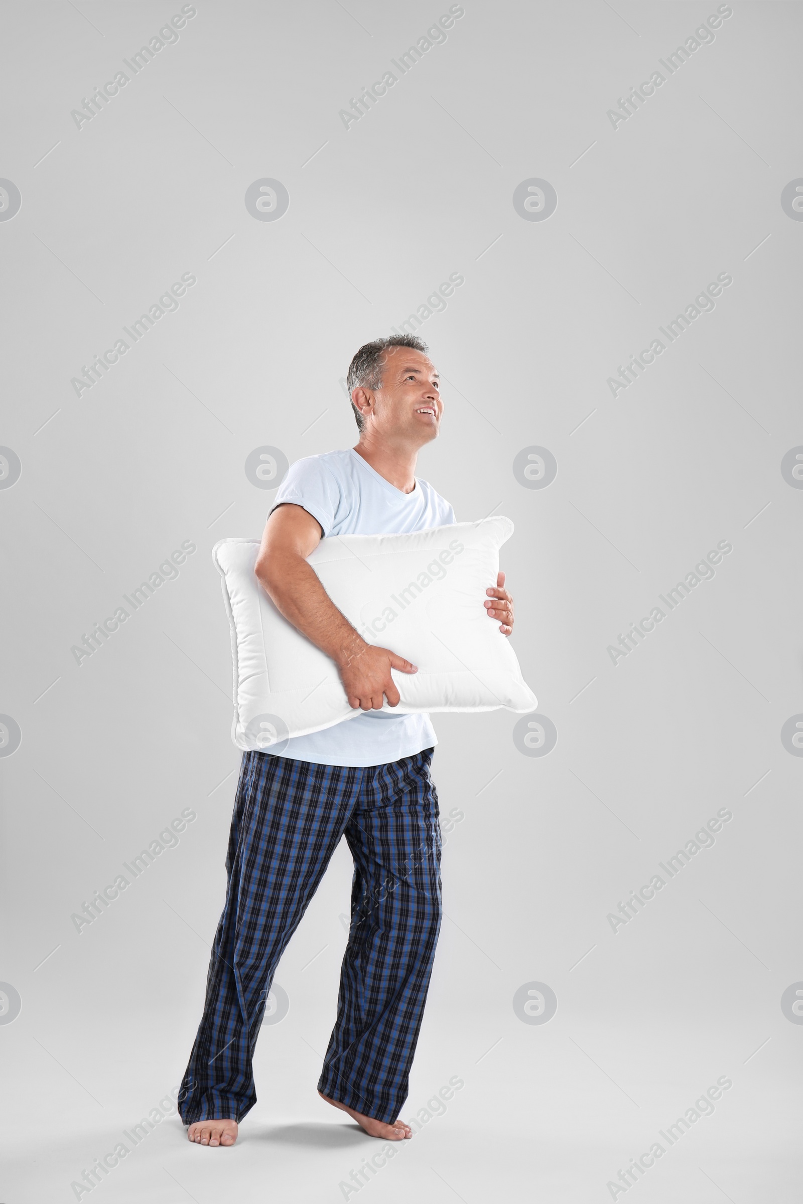 Photo of Man holding soft pillow on light background