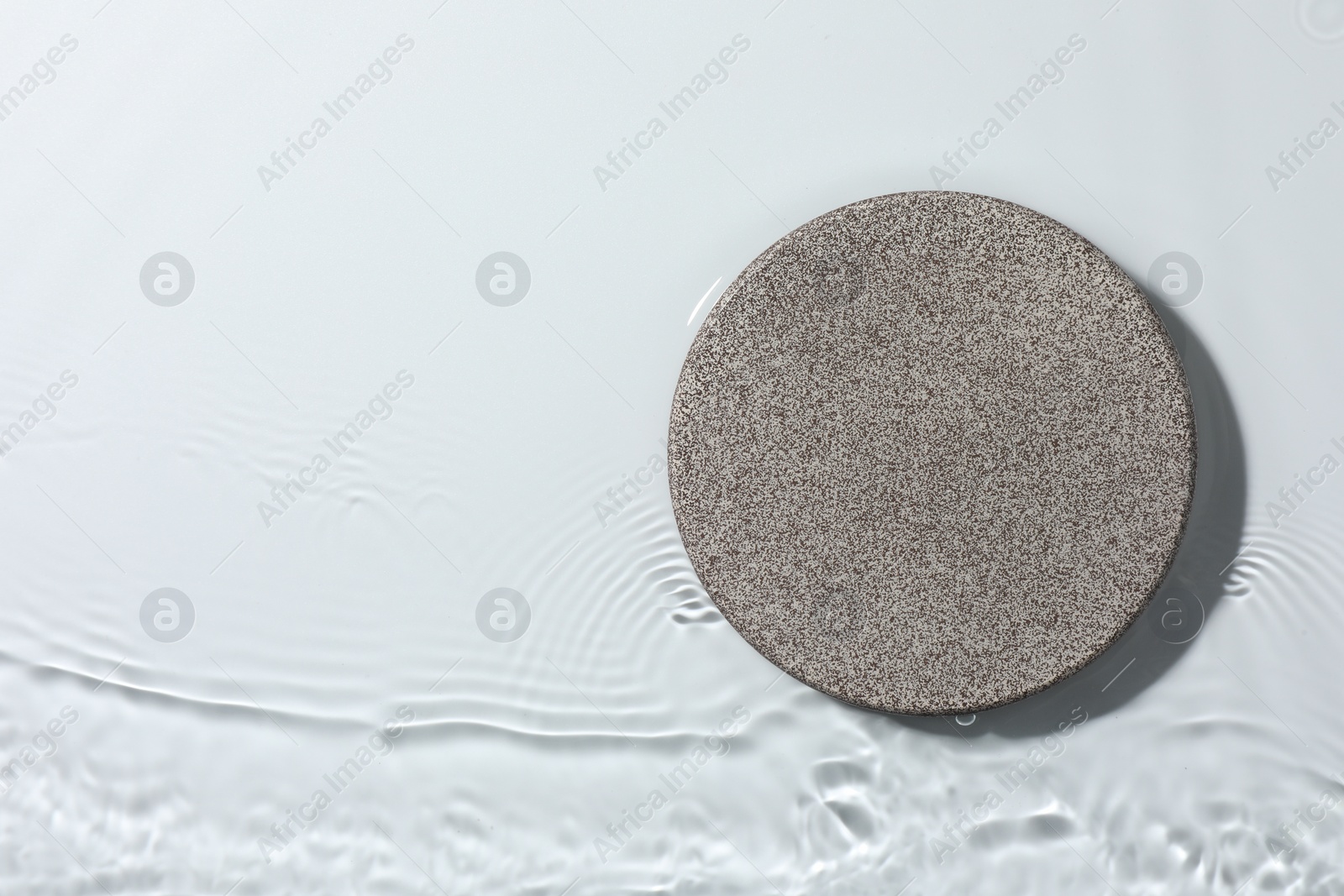 Photo of Presentation of product. Stone podium in water on white background, top view. Space for text