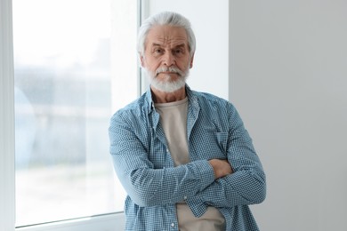 Portrait of happy grandpa with grey hair near window indoors