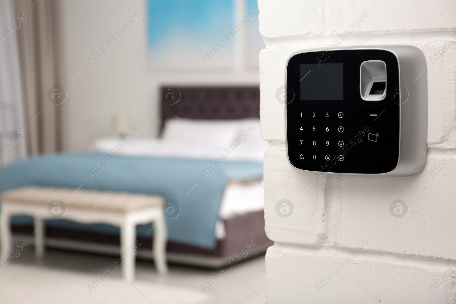 Photo of Modern alarm system with fingerprint scanner on brick wall in house. Space for text