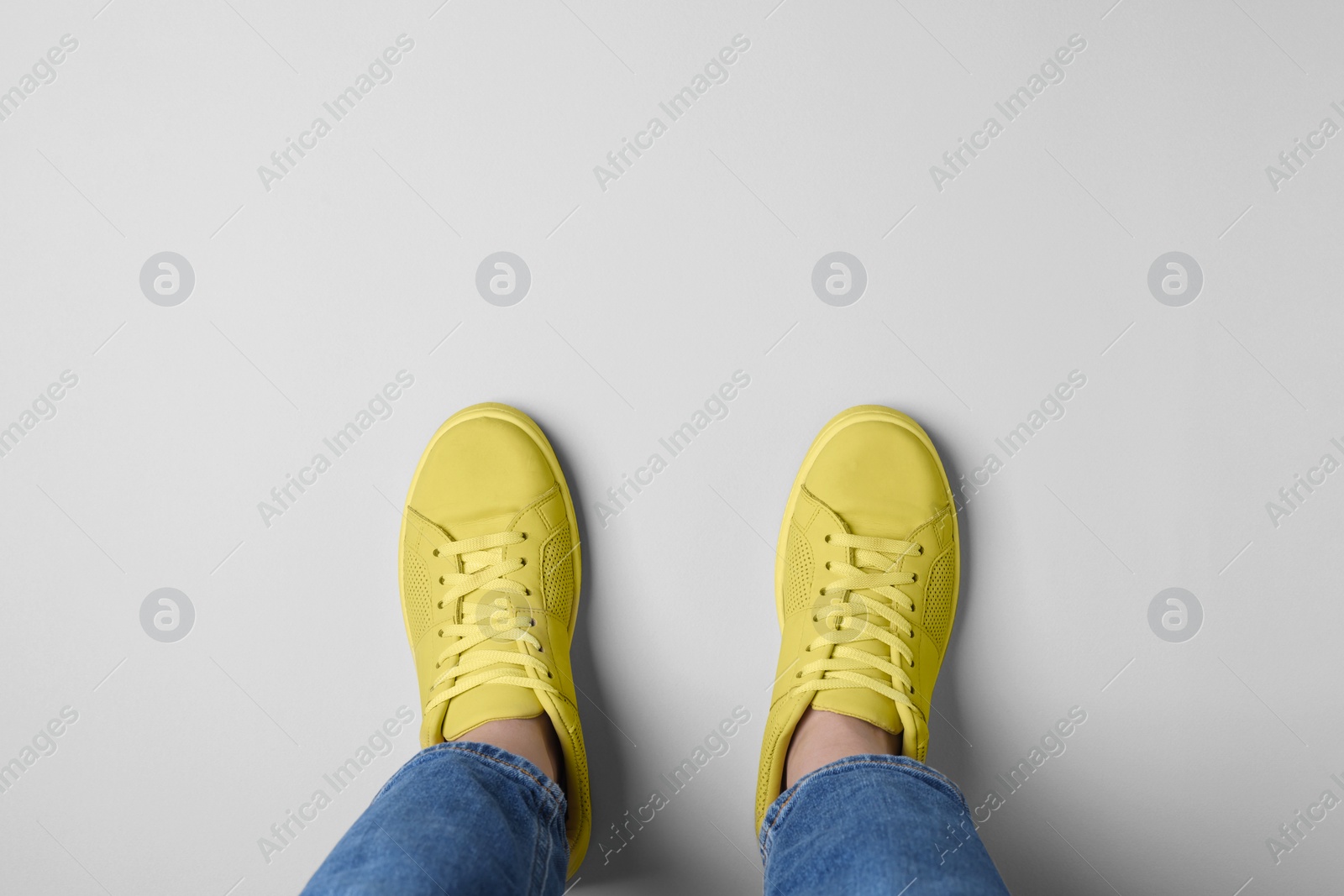 Photo of Woman in stylish sneakers on light background, top view