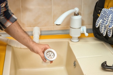 Professional plumber fixing sink, closeup of hand