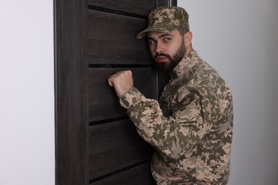 Photo of Military commissariat representative knocking on wooden door