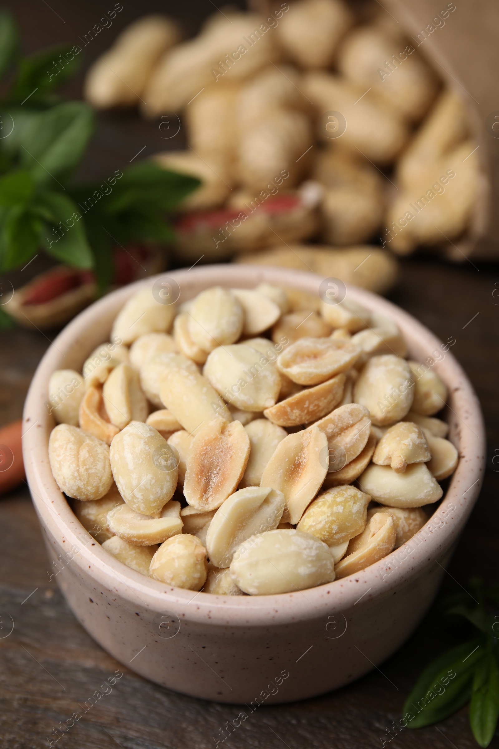 Photo of Fresh peeled peanuts in bowl on wooden table, closeup