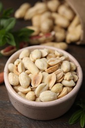 Photo of Fresh peeled peanuts in bowl on wooden table, closeup