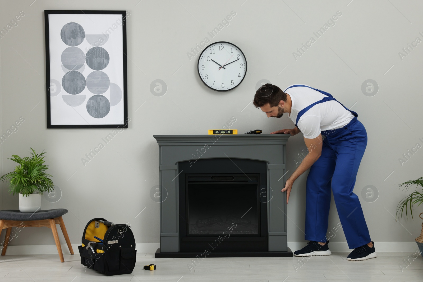 Photo of Professional technician installing electric fireplace in room