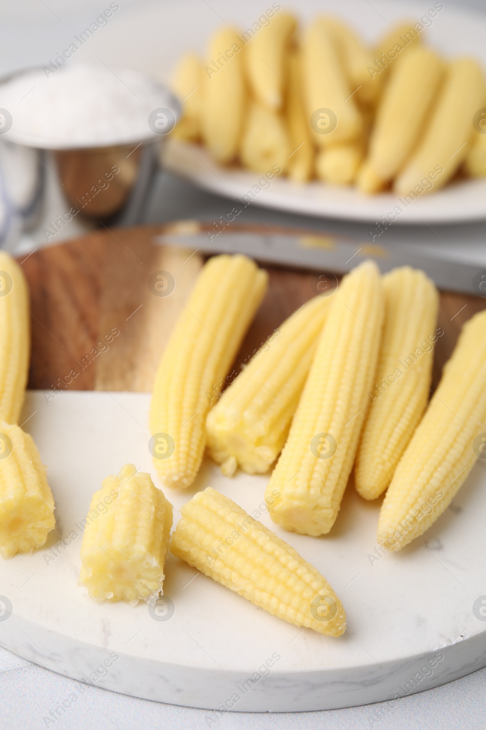 Photo of Tasty fresh yellow baby corns on white tiled table, closeup