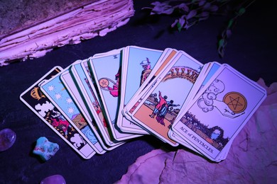 Photo of Tarot cards and old book on dark table, color toned