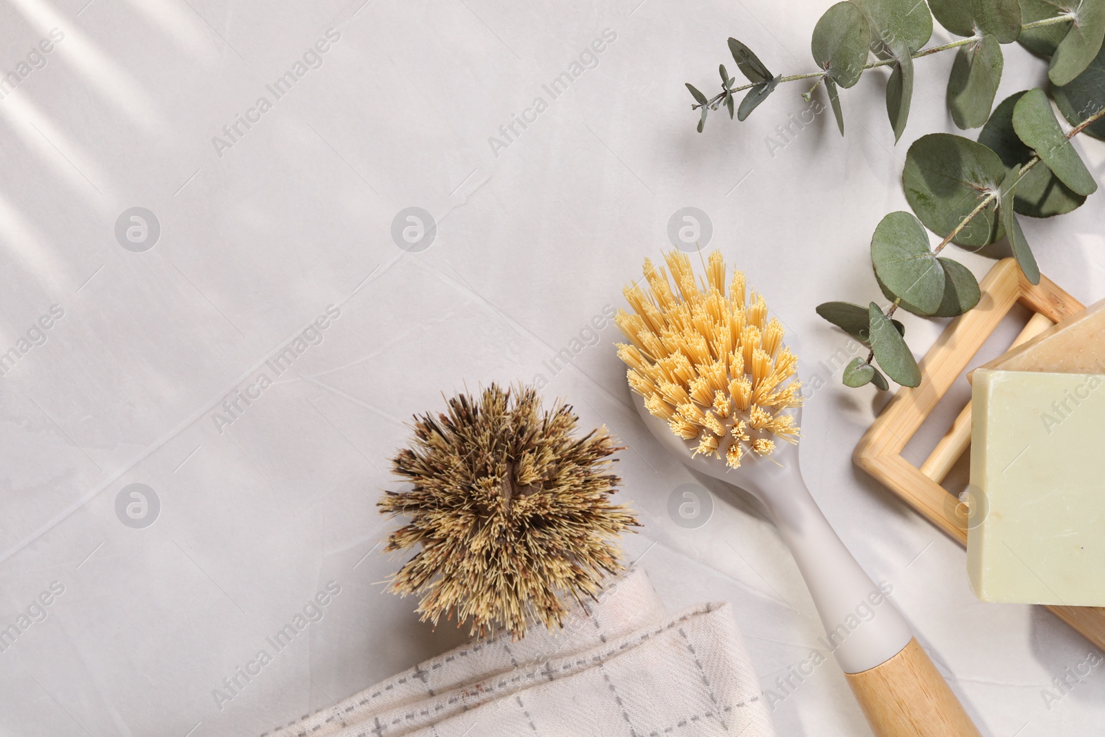 Photo of Cleaning brushes, soap bars and eucalyptus leaves on white table, flat lay. Space for text