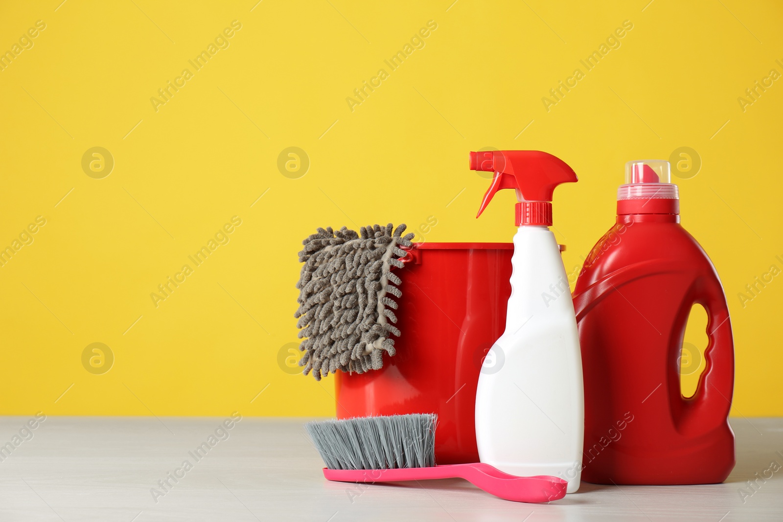 Photo of Bucket, cleaning products and tools on grey table. Space for text