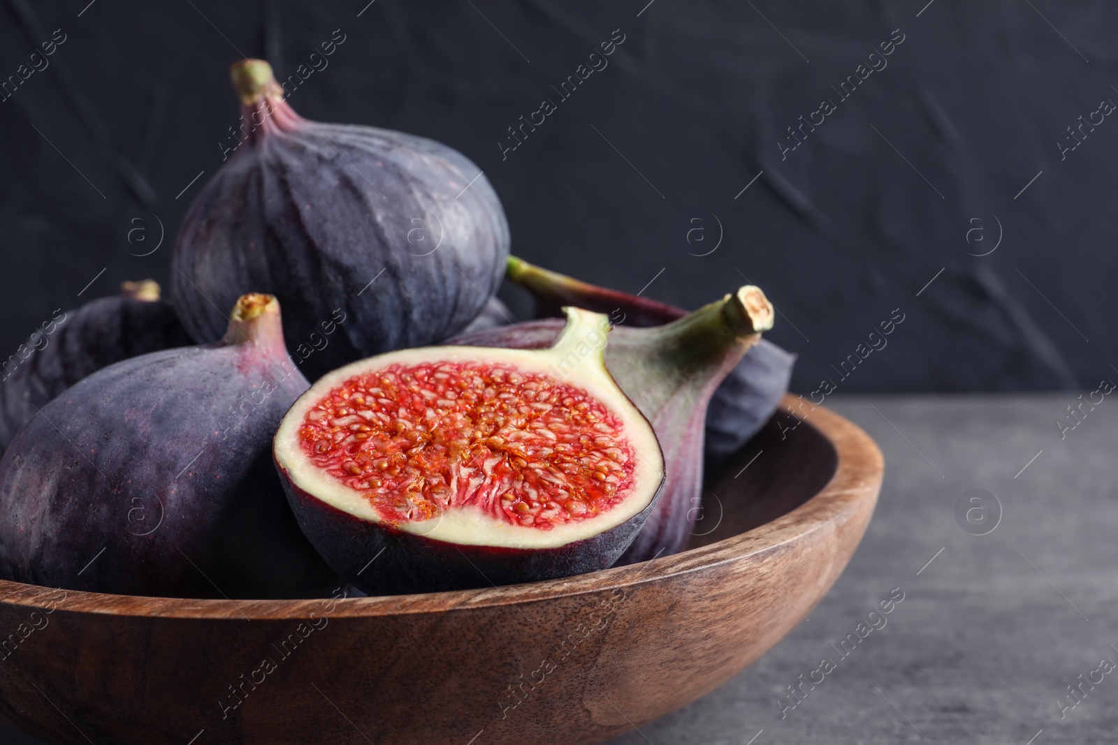 Photo of Bowl with fresh ripe figs on gray table. Tropical fruit