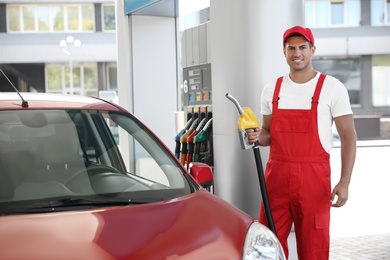 Photo of Worker with fuel pump nozzle near car at modern gas station