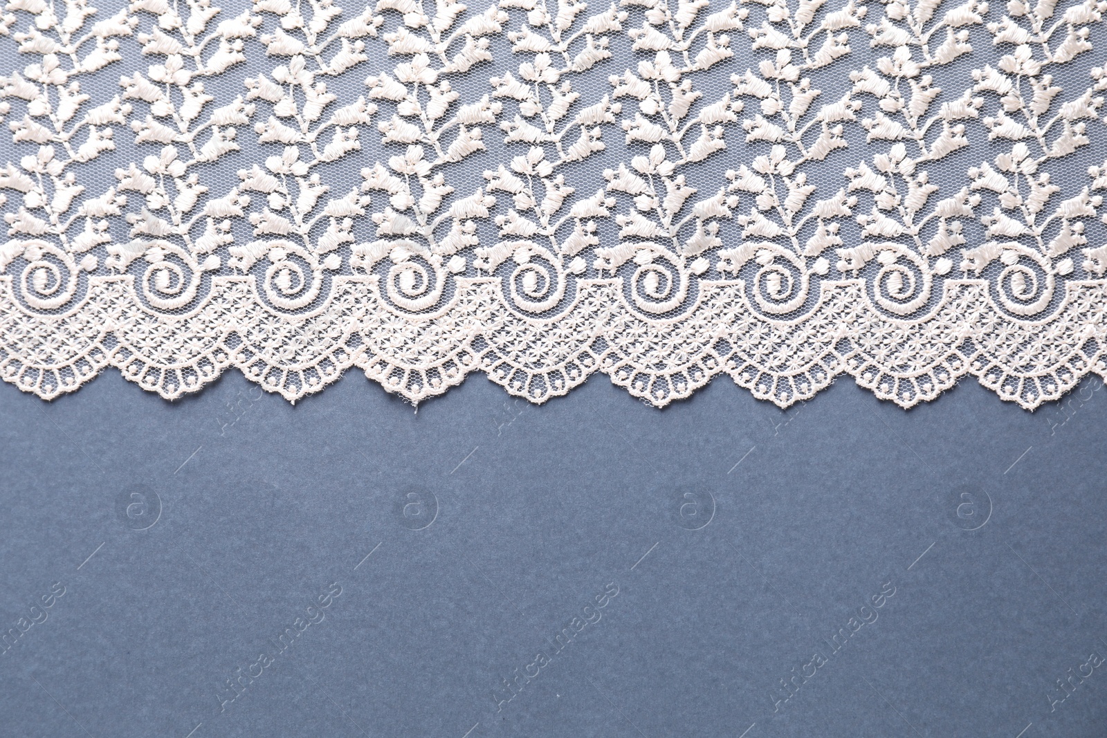 Photo of White lace on light blue background, top view. Space for text