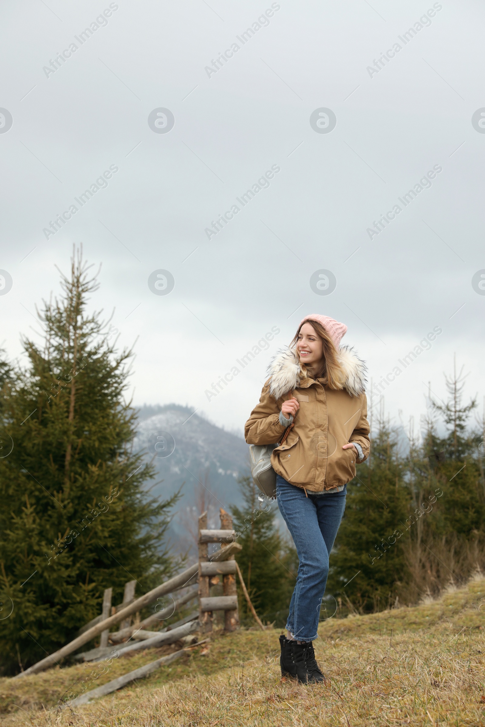 Photo of Young woman in warm clothes near conifer forest. Winter vacation