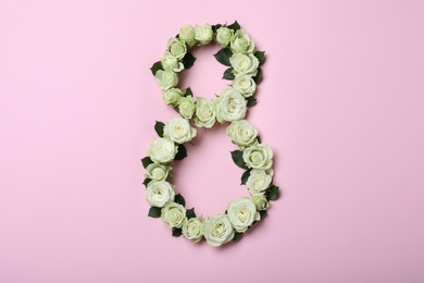 Photo of Number 8 made with white roses on pink background, flat lay. International Women's day