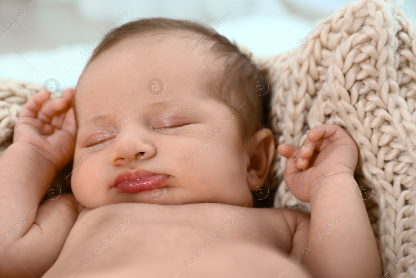 Photo of Cute little baby sleeping on knitted plaid in cradle