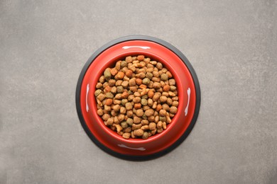 Dry dog food in feeding bowl on beige floor, top view