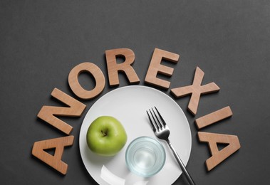 Photo of Flat lay composition with word Anorexia of wooden letters and table setting on dark grey background
