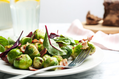 Photo of Delicious Brussels sprouts with bacon on table, closeup