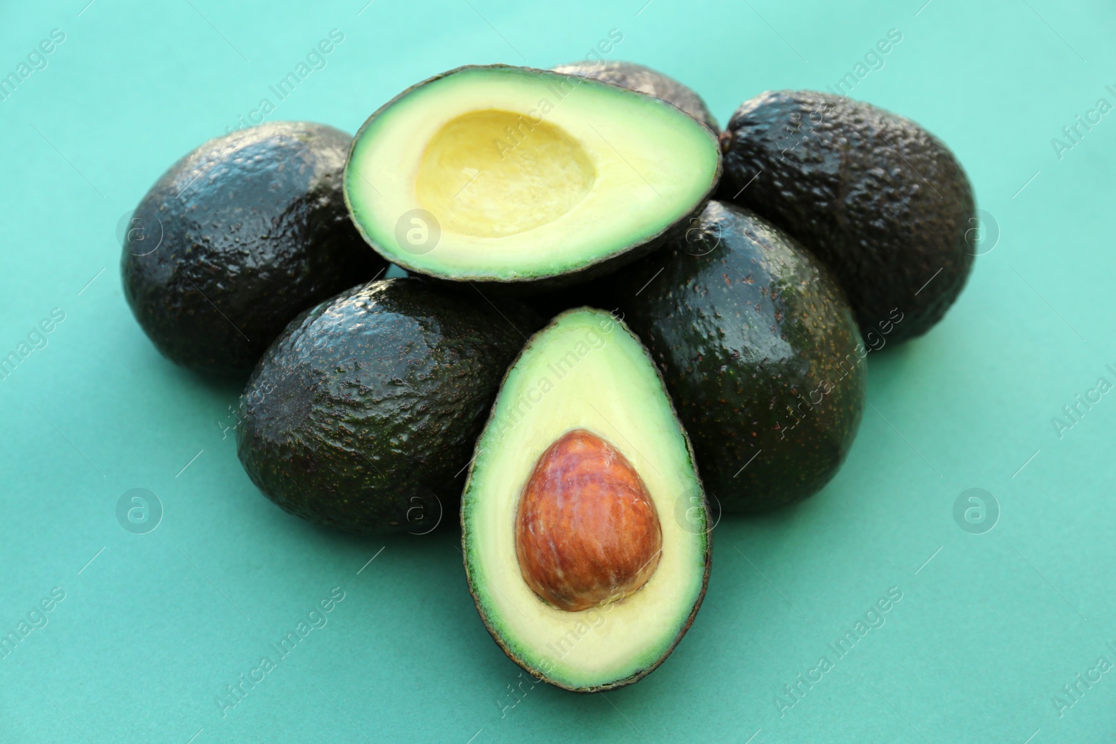 Photo of Tasty whole and cut avocados on turquoise background