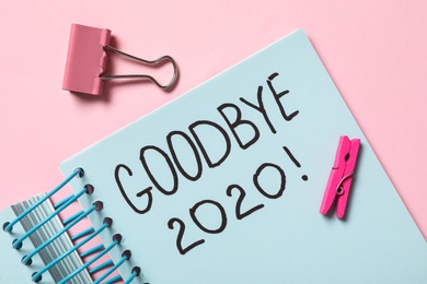 Photo of Notebook with text Goodbye 2020 on pink background, flat lay
