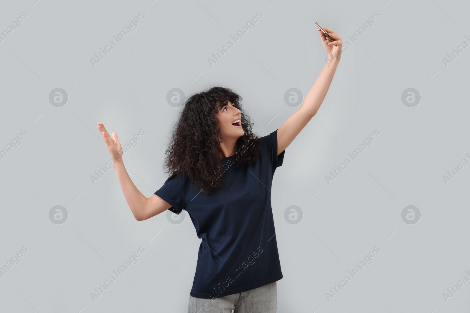 Photo of Beautiful young woman taking selfie on light grey background