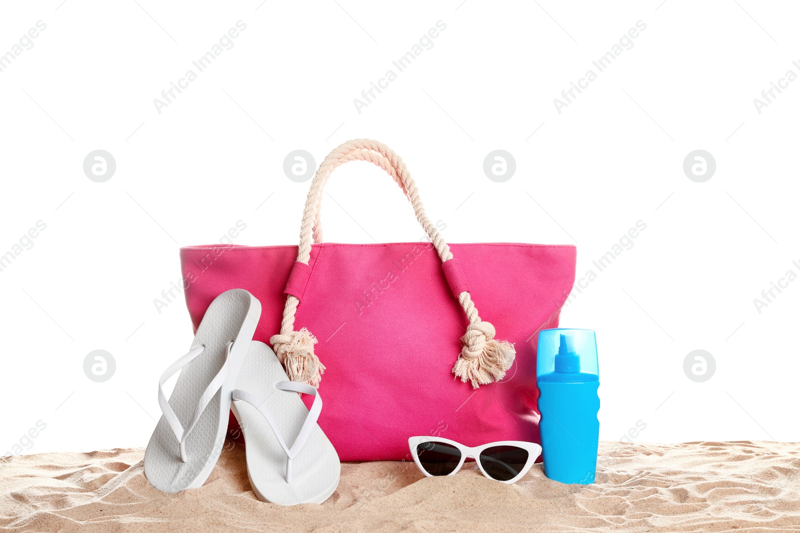 Photo of Stylish coral bag and beach accessories on sand against white background