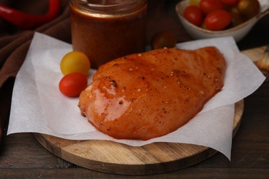 Photo of Fresh marinade and raw chicken fillets on wooden table