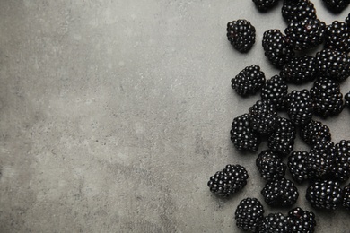 Photo of Tasty ripe blackberries on grey table, top view with space for text