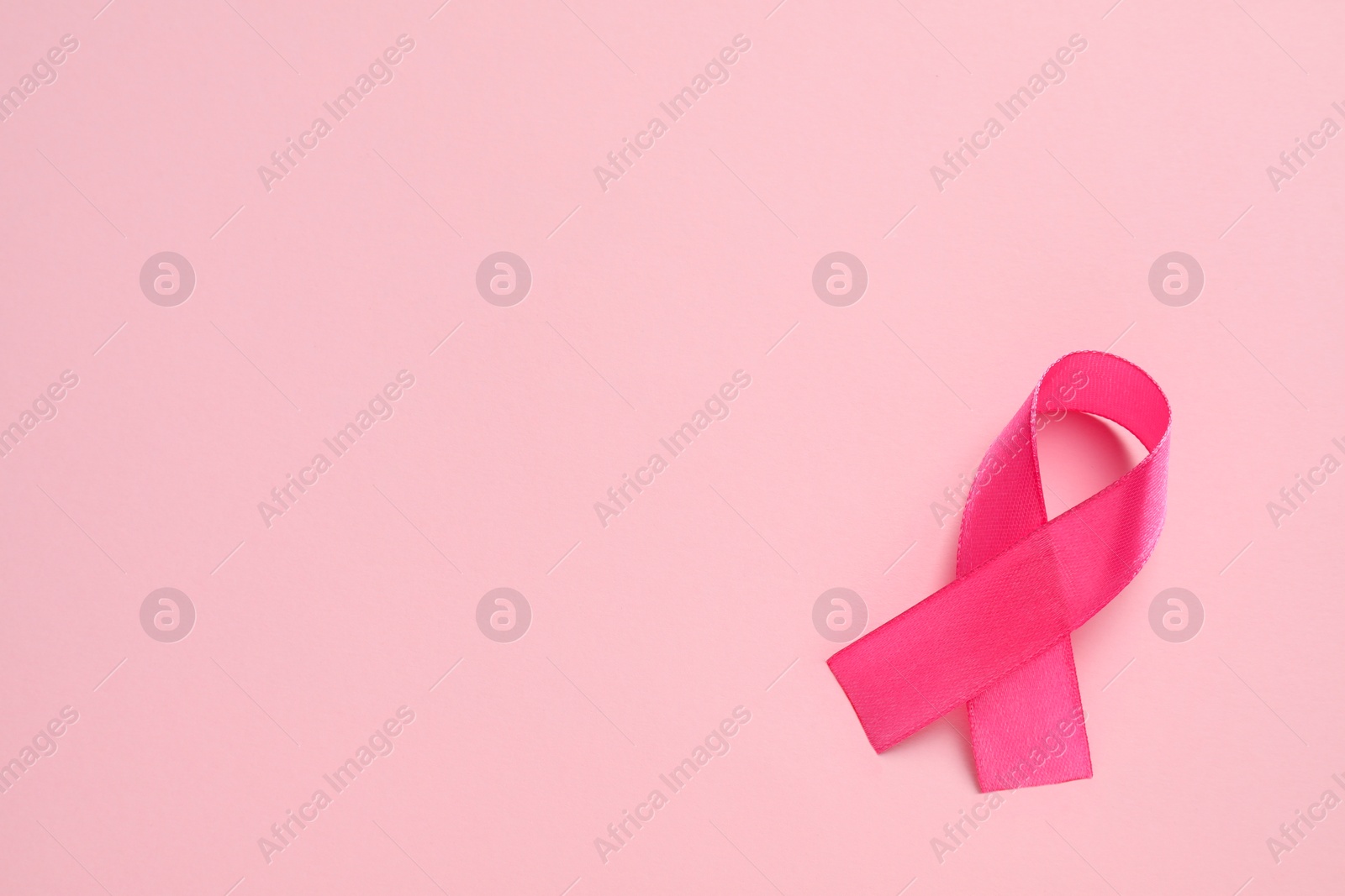 Photo of Pink ribbon on color background, top view and space for text. Breast cancer awareness