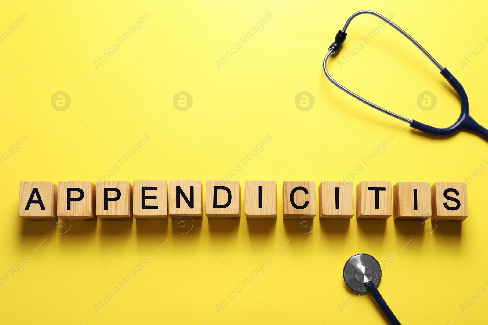 Photo of Word Appendicitis made of wooden cubes and stethoscope on yellow background, flat lay