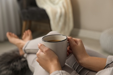 Photo of Woman with cup of hot drink resting at home, closeup