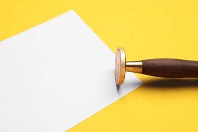 One stamp tool and sheet of paper on yellow background, closeup. Space for text