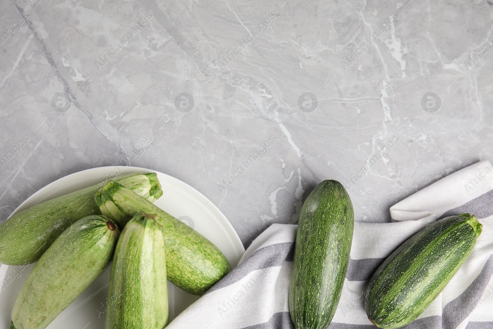 Photo of Flat lay composition with fresh ripe zucchini on grey marble background. Space for text