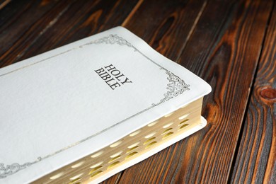 Old hardcover Bible on wooden table, closeup. Religious book