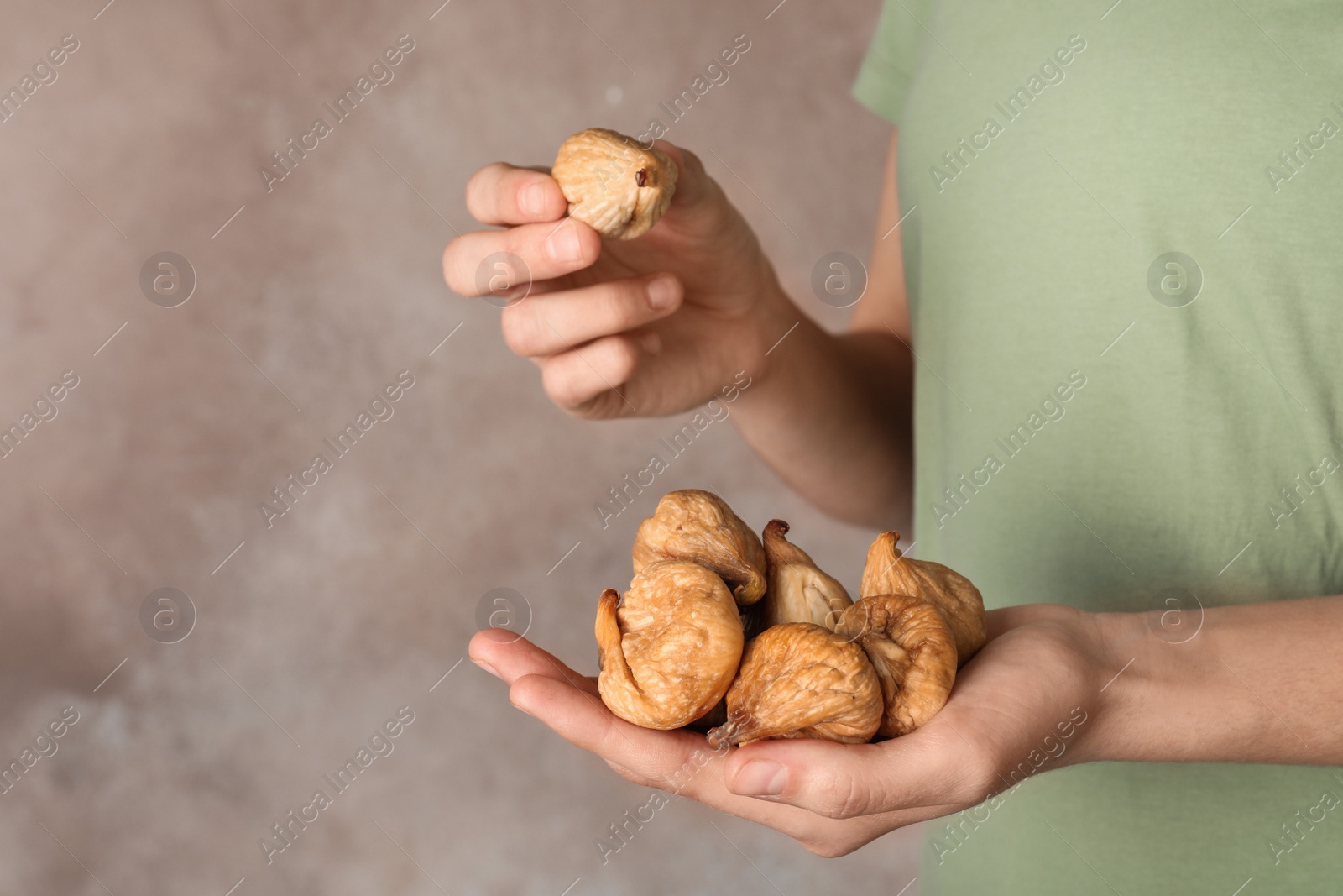 Photo of Woman holding handful of dried figs on color background, space for text. Healthy fruit