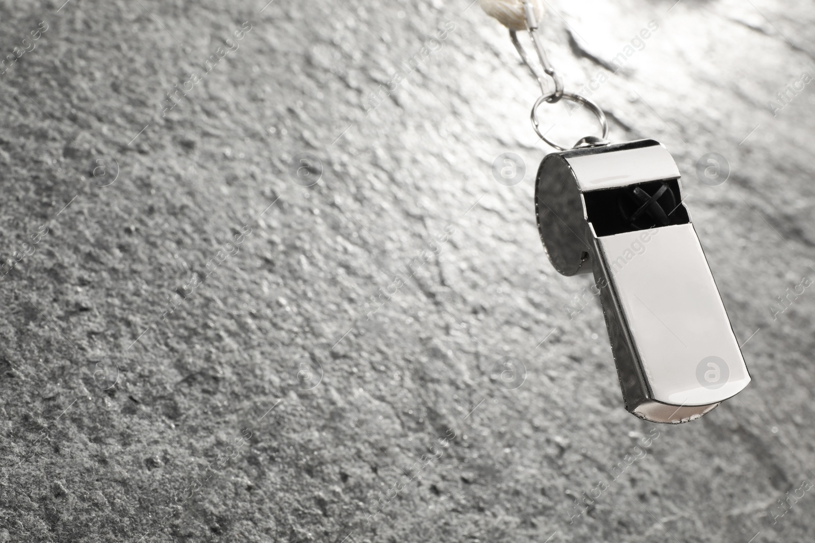 Photo of Referee equipment. Metal whistle on grey textured background, closeup and space for text