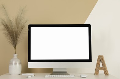 Photo of Modern computer, decor and office supplies on white wooden table near color wall