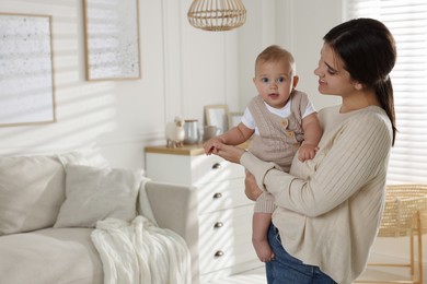 Photo of Happy young mother with her baby in living room. Space for text